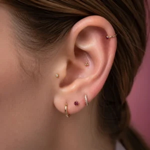 Piercing Types & Charts hub hero, a clear ear showing helix, tragus, conch and lobe placements in soft studio light