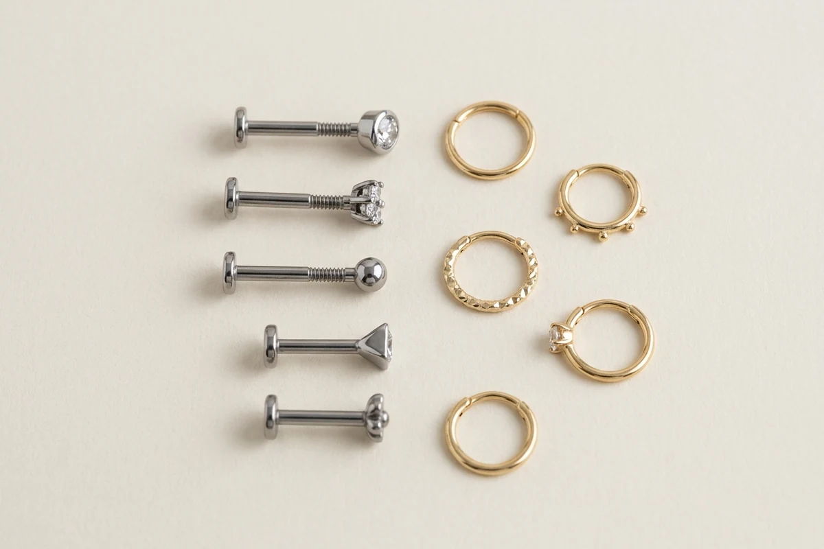 Flat lay of titanium flat-back studs and small gold hoops on a light surface